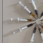 10 syringes laid out in a circle demonstrating different colours of CBD oil