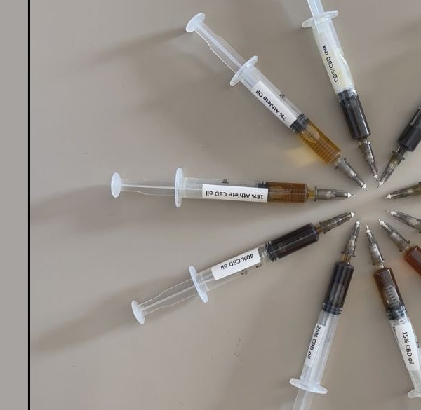 10 syringes laid out in a circle demonstrating different colours of CBD oil