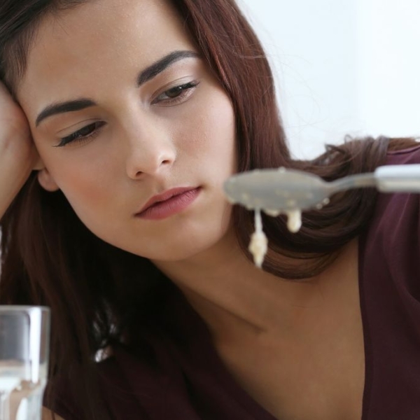 Woman looking disgusted at a spoon of food