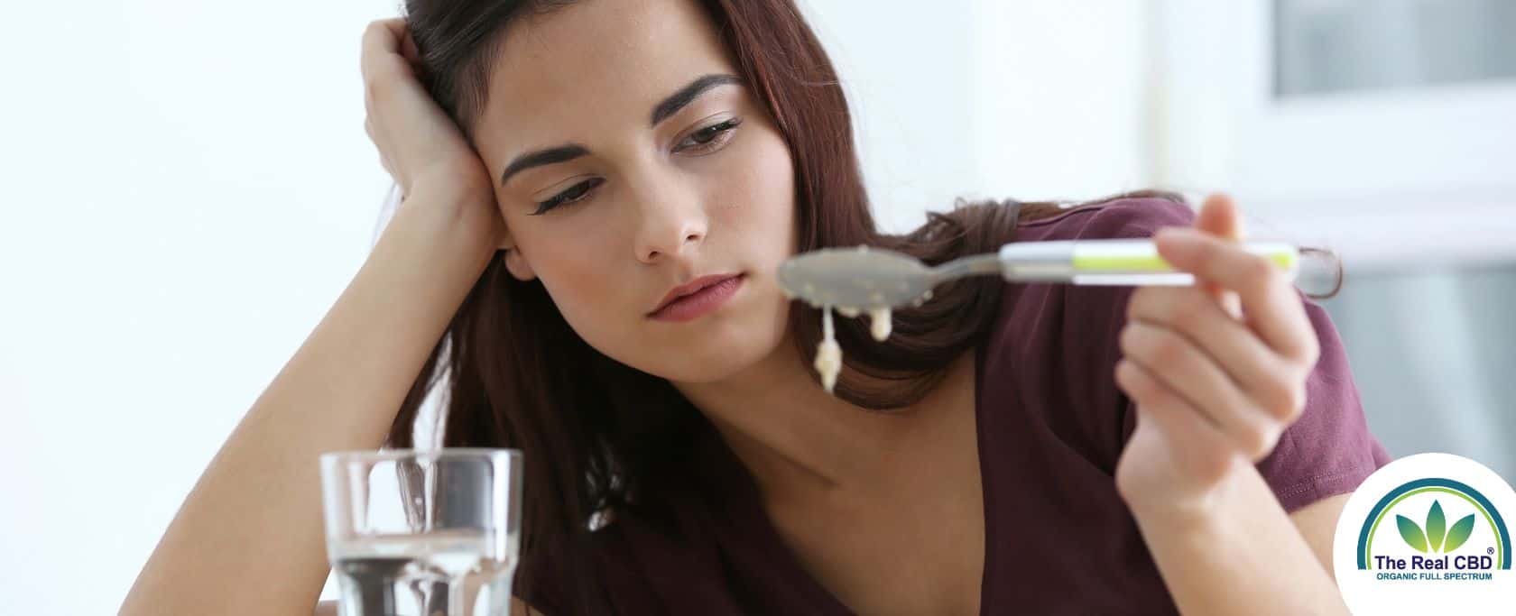 Woman looking disgusted at a spoon of food