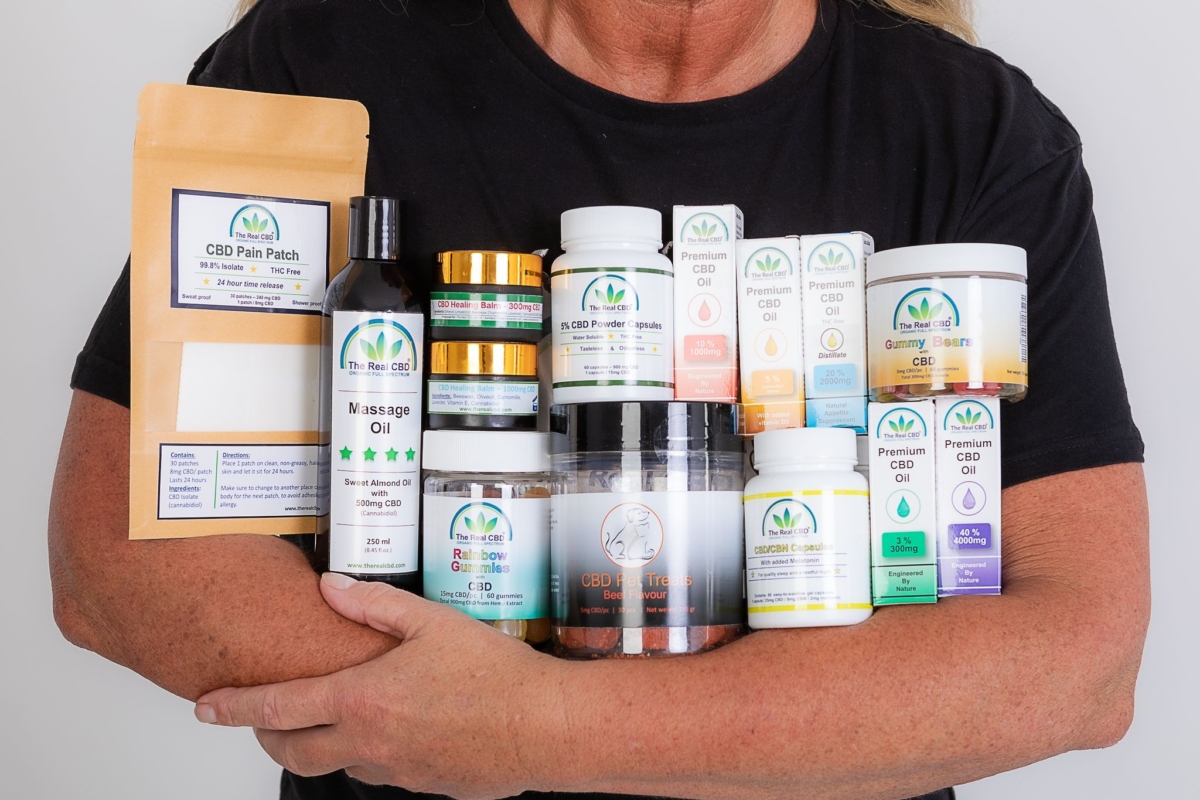 Woman in black t-Shirt holding many CBD products in her arms - The Real CBD Brand