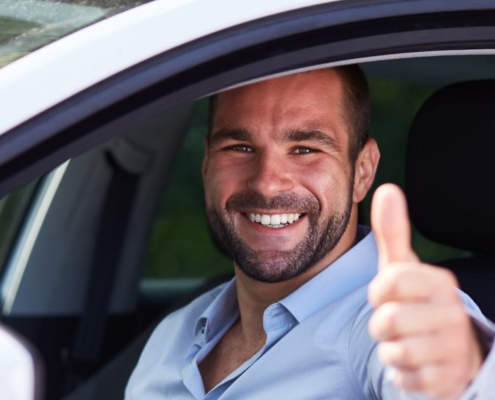 Un homme lève le pouce dans une voiture