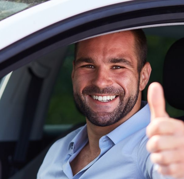 Un homme lève le pouce dans une voiture