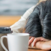 Femme dormant sur une table avec plusieurs tasses de café dessus