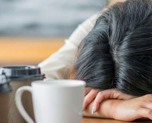 Femme dormant sur une table avec plusieurs tasses de café dessus