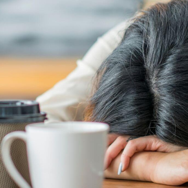 Frau schlafend auf Tisch mit mehreren Kaffeetassen auf