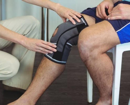 Nurse holding sick knee on patient sitting down