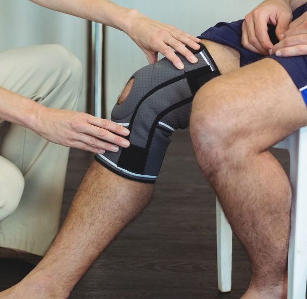 Nurse holding sick knee on patient sitting down