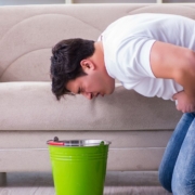 Man bent over a bucket ready to puke