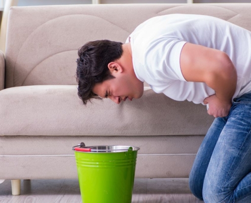 Homme penché sur un seau prêt à vomir