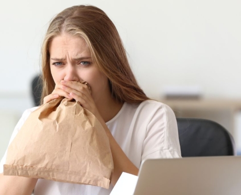 Femme soufflant dans un sac en papier dans un bureau