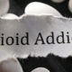 Opioid Addiction on a white paper rip onto of white pills