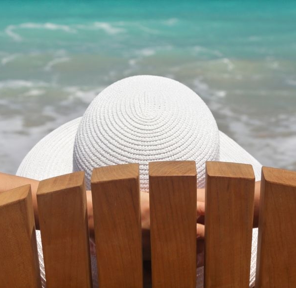 Femme assise sur une chaise de plage au bord de la mer, en train de se détendre