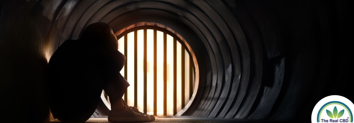 Person sitting in a tunnel with head between the knees