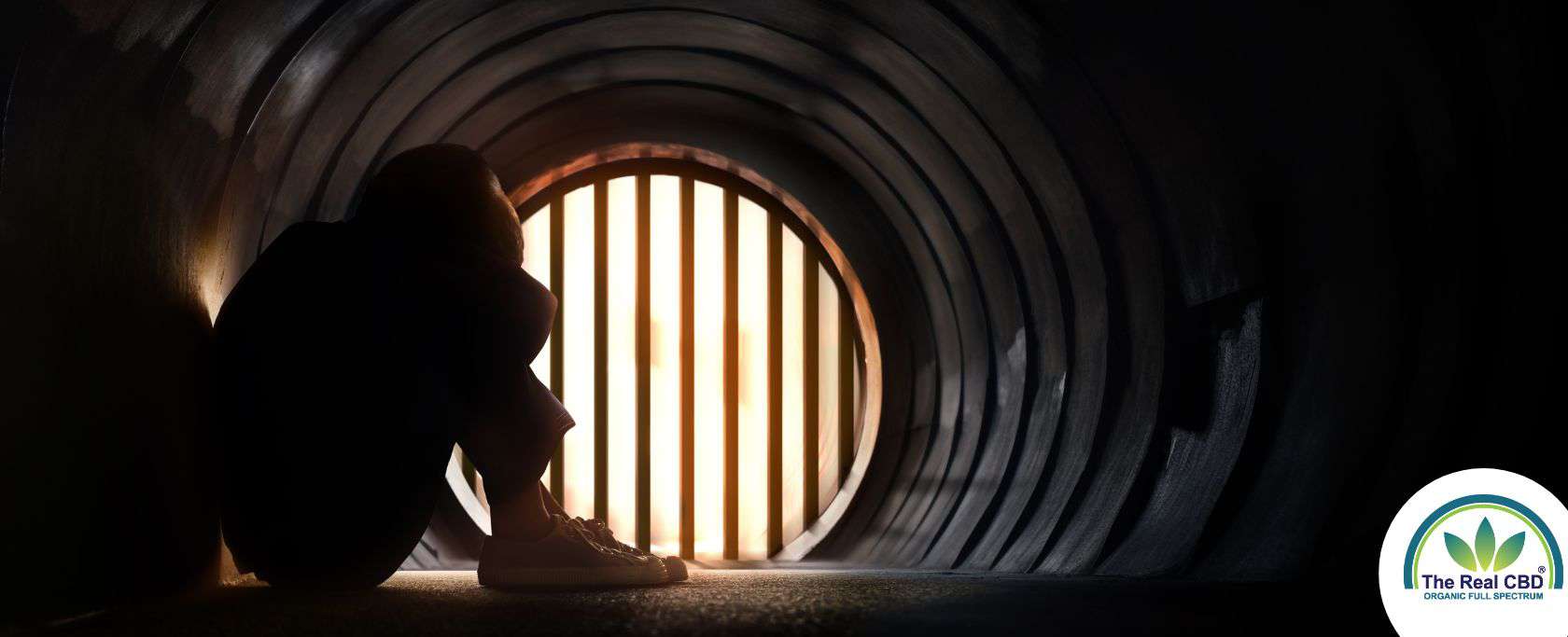 Person sitting in a tunnel with head between the knees