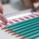 Pencils and paper clips laying in neat lines with a ruler fingers organising it