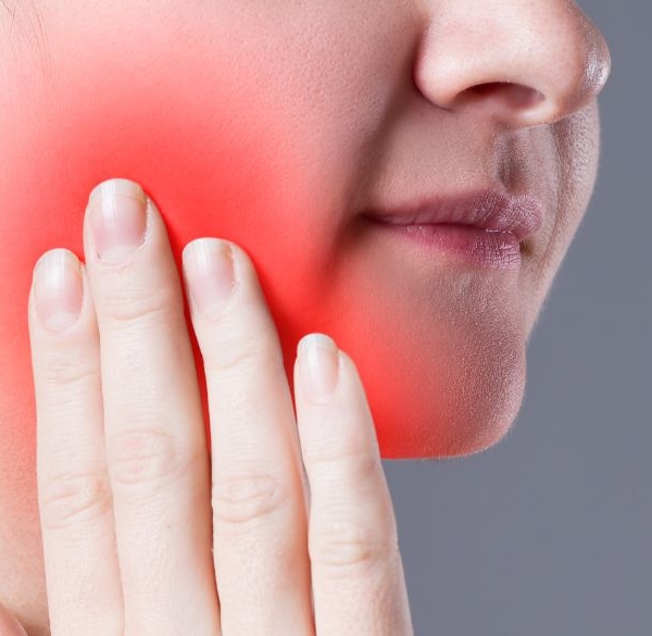 Woman holding cheek in tooth pain