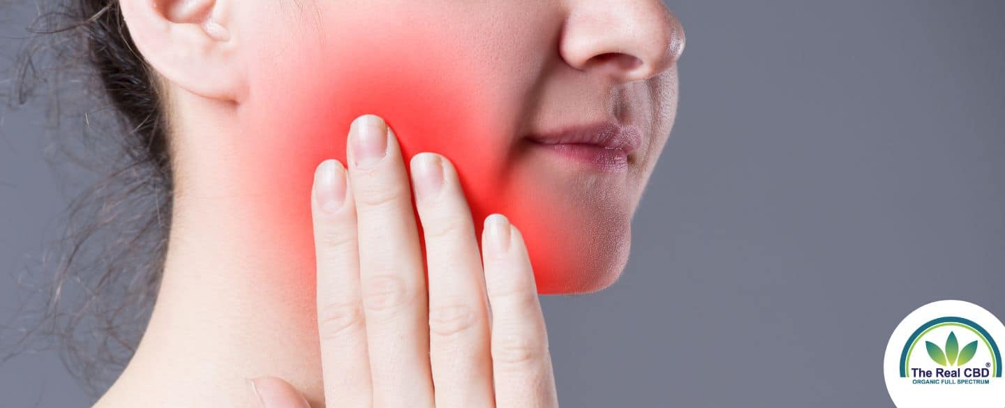 Woman holding cheek in tooth pain