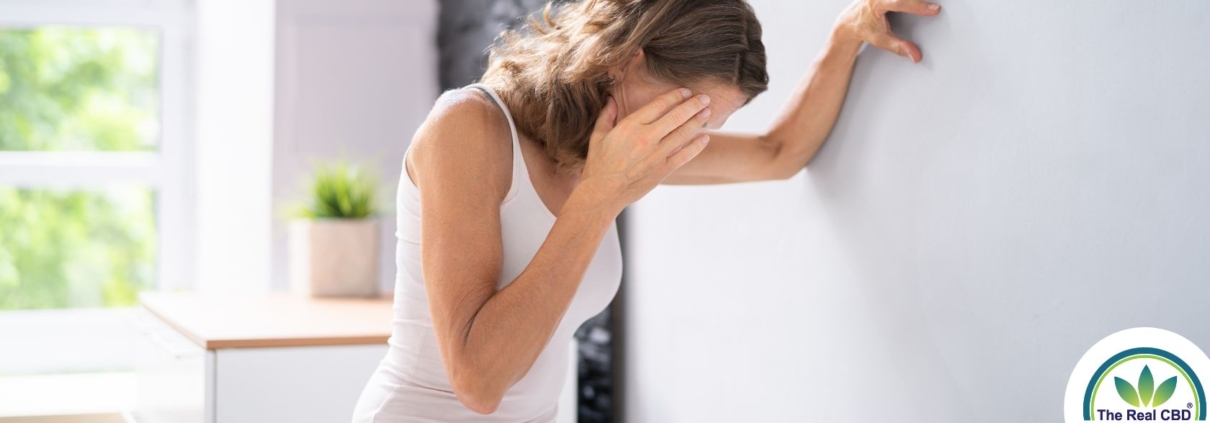 Femme adossée au mur, se touchant la tête en signe d'épuisement