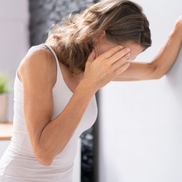 Femme adossée au mur, se touchant la tête en signe d'épuisement