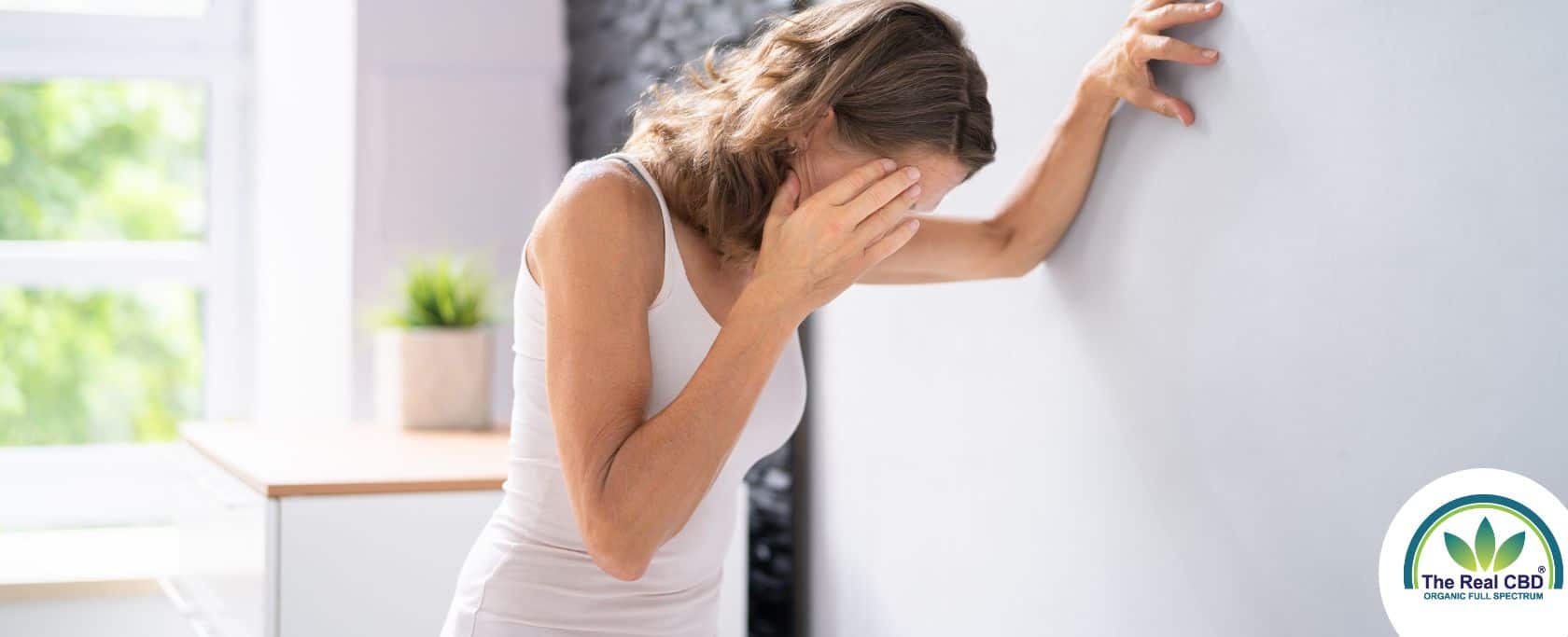 Femme adossée au mur, se touchant la tête en signe d'épuisement