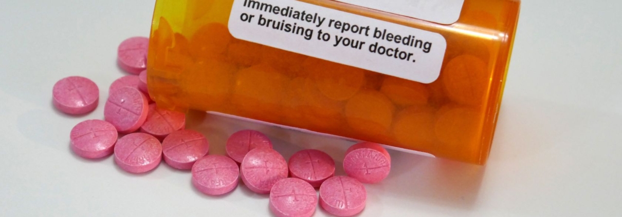 Close-up of pink tablets coming out of a orange jar