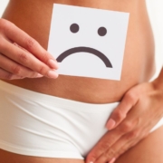 Woman holding an unhappy sign in front of her pelvis