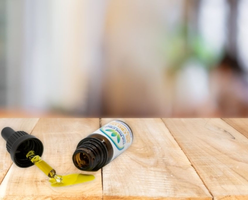 Tipped over CBD bottle with oil running out in focus.