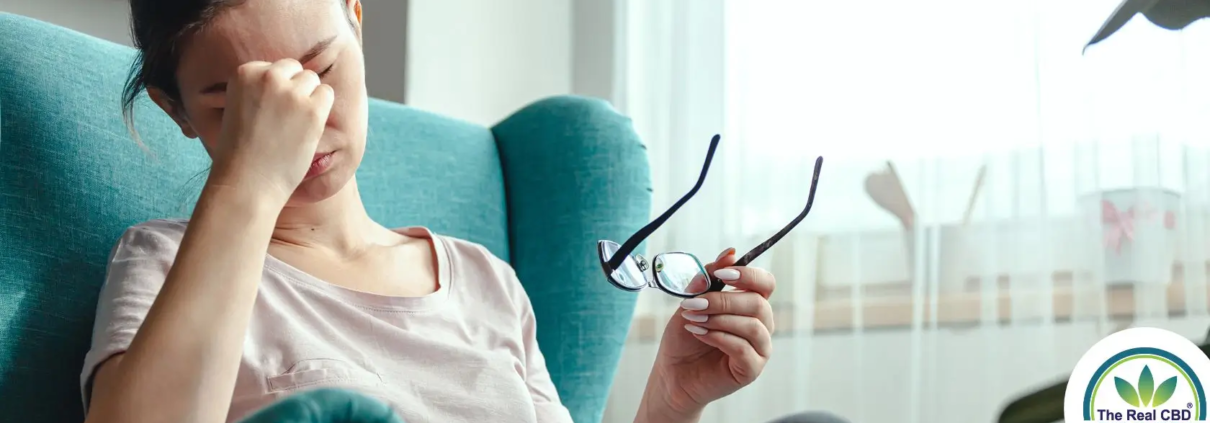 Woman sitting in easy chair, showing signs of a headache