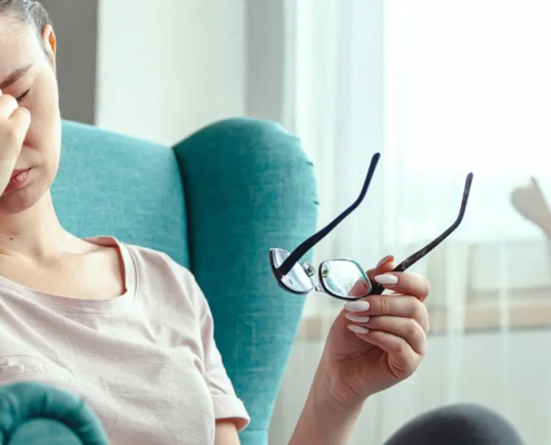 Woman sitting in easy chair, showing signs of a headache