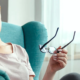 Woman sitting in easy chair, showing signs of a headache