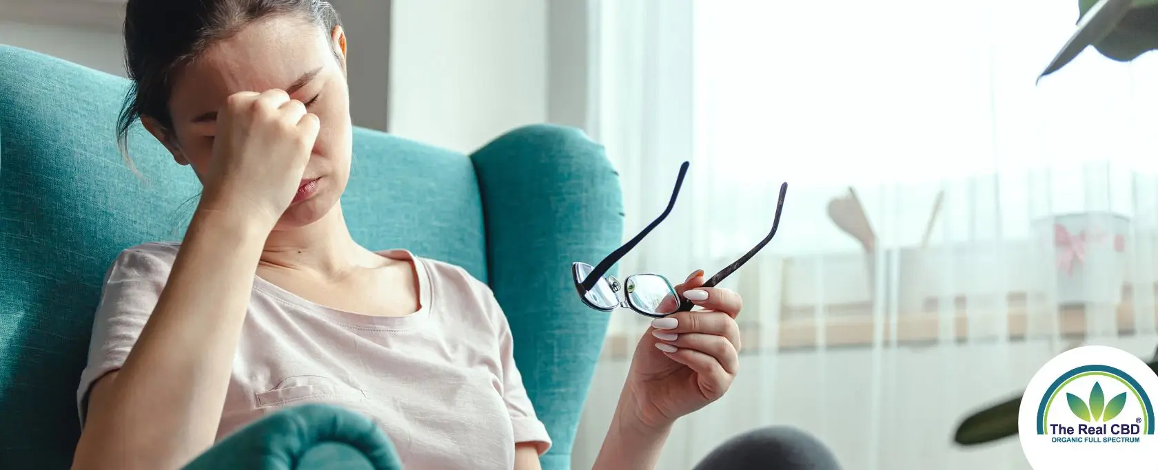 Woman sitting in easy chair, showing signs of a headache