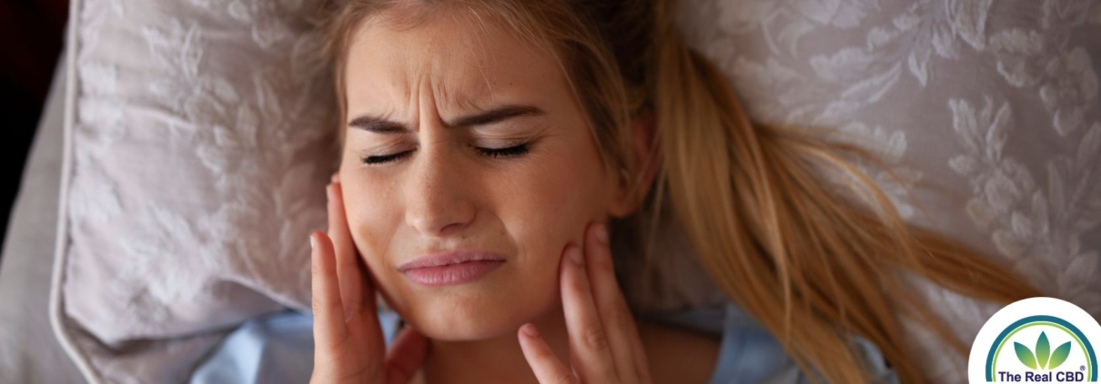 Woman holding her cheeks in pain after teeth grinding