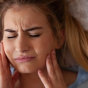 Une femme se tient les joues de douleur après avoir grincé des dents