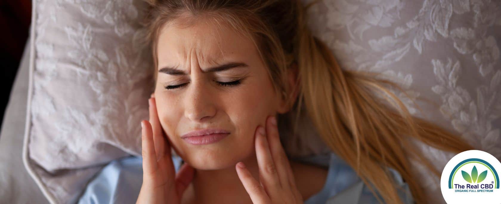 Une femme se tient les joues de douleur après avoir grincé des dents