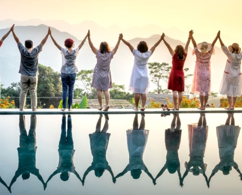 A row of happy people standing celebrating life on the edge of a pool