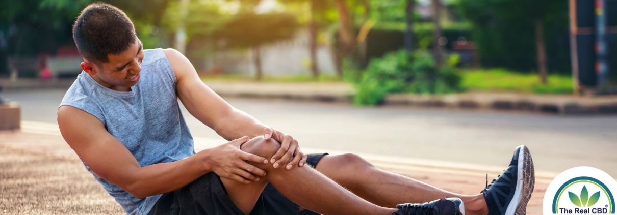 Athlete sitting on the ground, holding his knee in agony