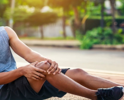 Athlete sitting on the ground, holding his knee in agony