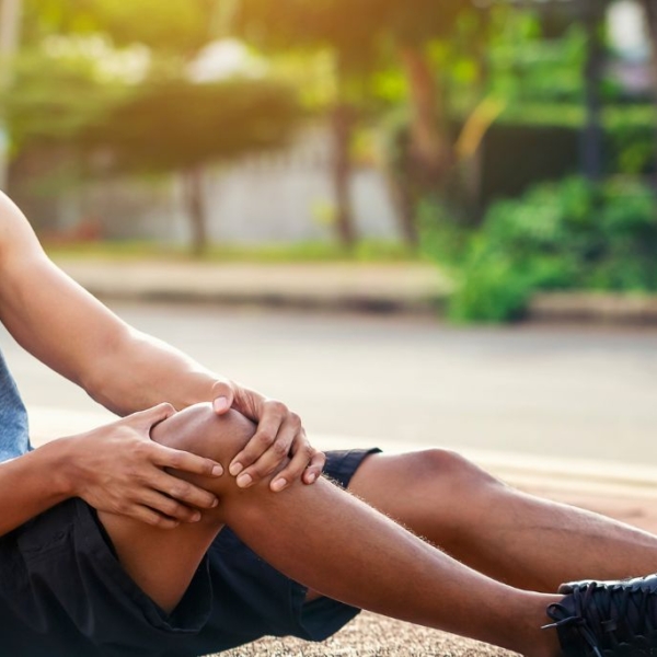 Athlete sitting on the ground, holding his knee in agony