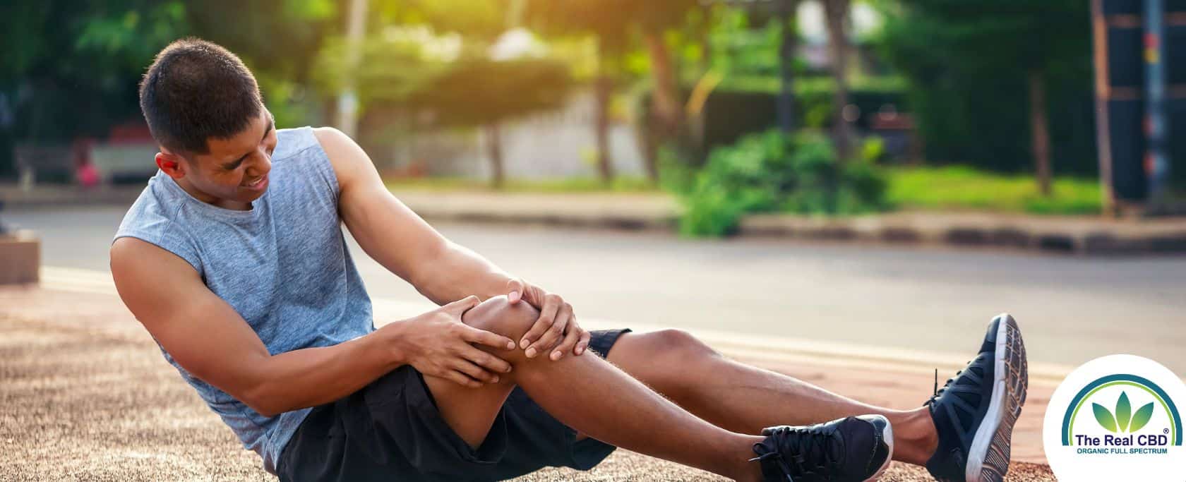 Sportler sitzt auf dem Boden und hält sich das Knie vor Schmerzen