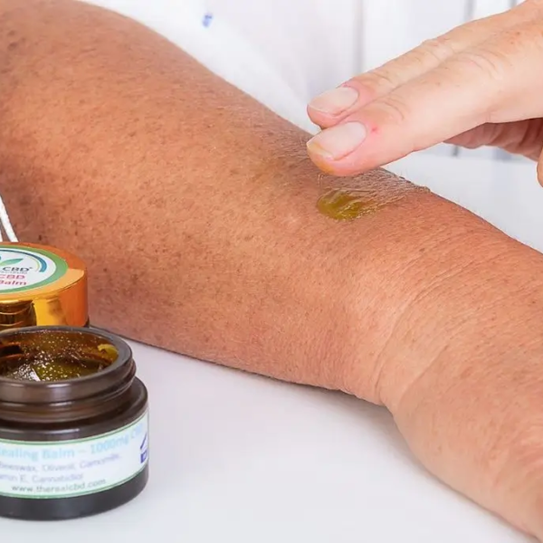 Hand, die The Real CBD Balsam auf den Arm reibt