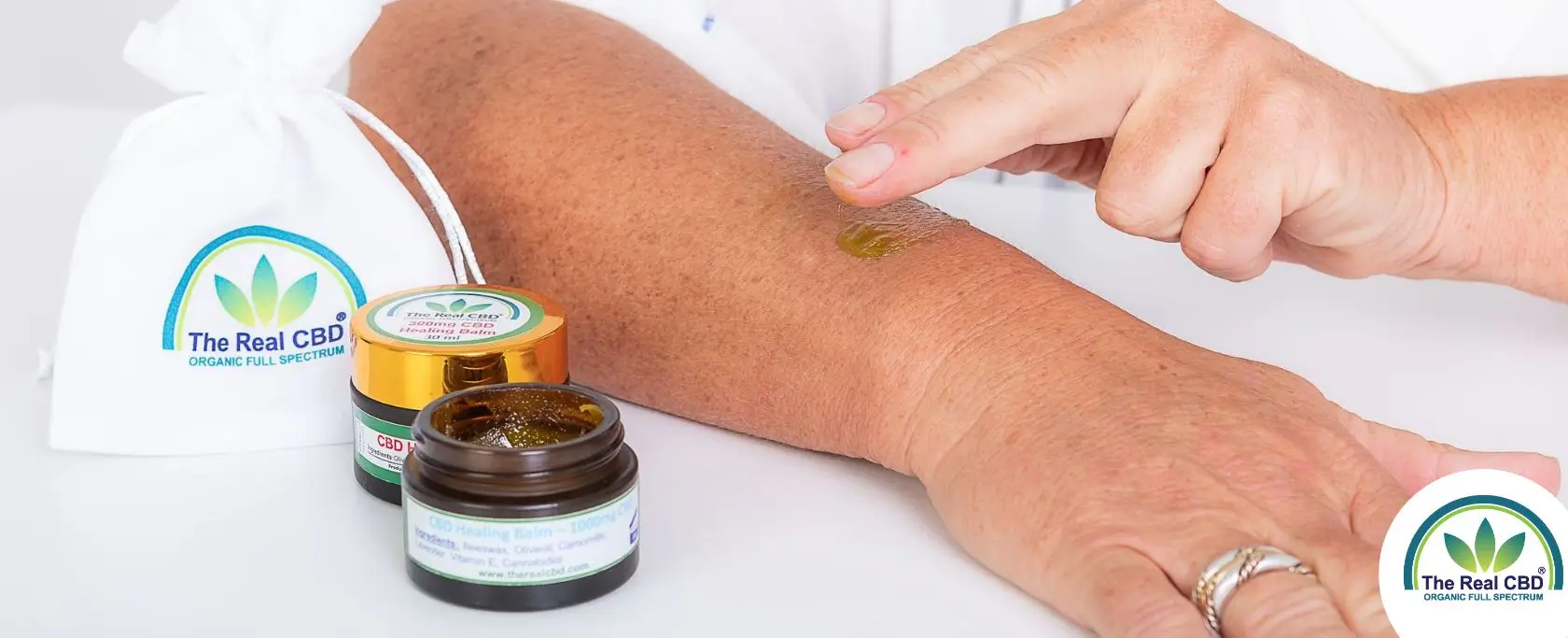 Hand, die The Real CBD Balsam auf den Arm reibt