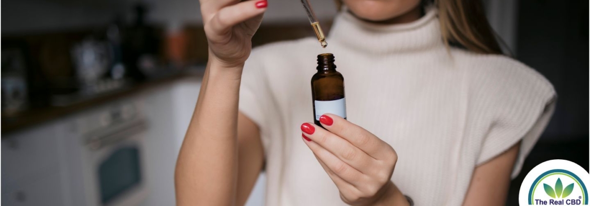 Woman holding dropper bottle taking oil before work