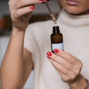 Woman holding dropper bottle taking oil before work