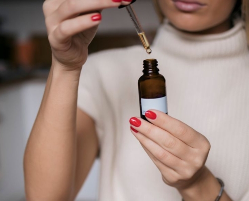 Woman holding dropper bottle taking oil before work