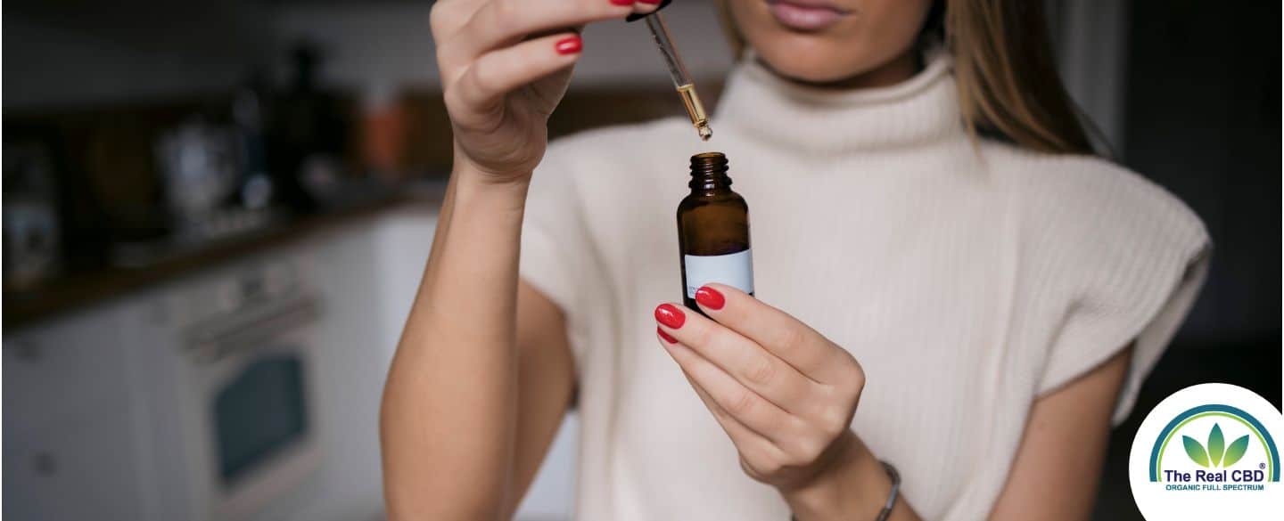 Woman holding dropper bottle taking oil before work