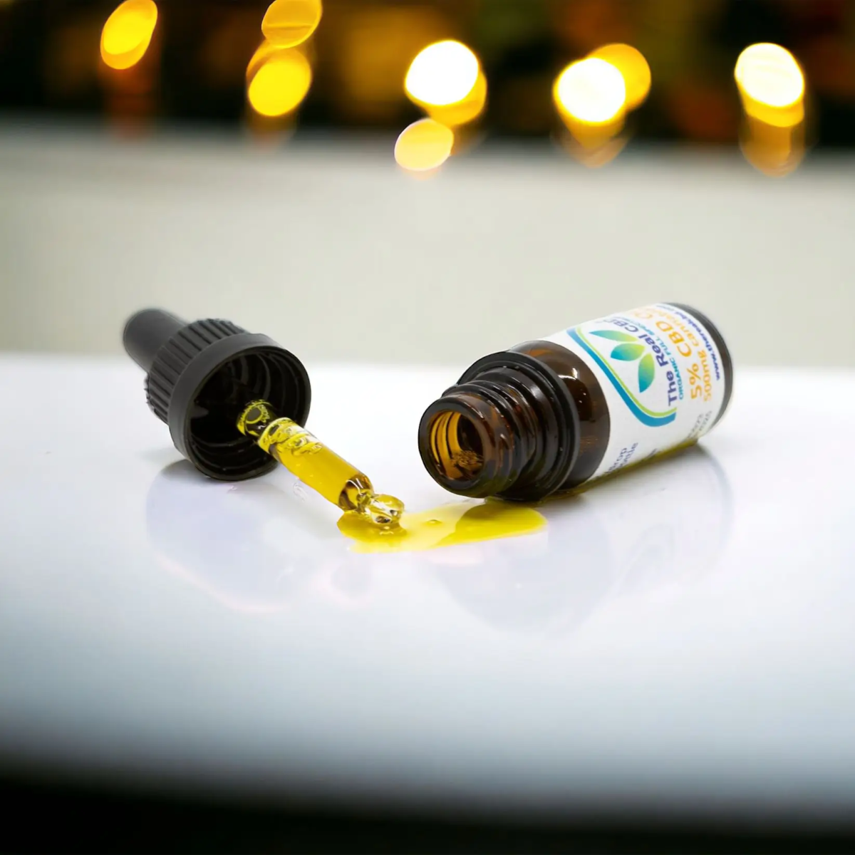 Tipped CBD oil with oil and pipette on a white surface - The Real CBD Brand