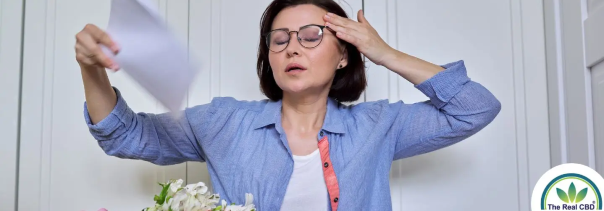 Woman having a hot flash, cooling herself with a paper