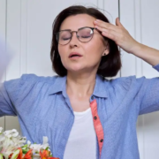 Woman having a hot flash, cooling herself with a paper