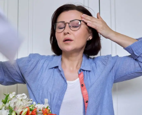 Woman having a hot flash, cooling herself with a paper